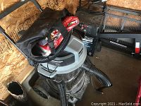 Photo of large wet/dry Shop Vac on wheels with attached hose, flexible vacuum hose, various vacuum accessories in storage bag