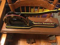 Photo of historical Master Mason Rock City Tobacco cutter mounted on a wooden shelf. Shows lettering and overall shape clearly.