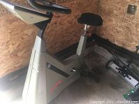 Side profile of the grey stationary bike showing frame, seat, pedals and console