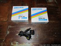 Two SQ11 Mini DV Cameras with USB cables and original boxes displayed on a wooden surface.