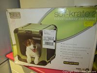 Box front showing dog in green soft-sided pet crate with mesh fabric and reinforced corners. Highlights features: fast setup, lightweight, washable, three entry points, heavy-duty mesh.