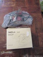 Skil sander wrapped in plastic and Tacklife sander boxed on wooden surface.