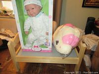 Photo showing the large wooden bed frame with the packaged baby doll and unicorn plush placed on top.