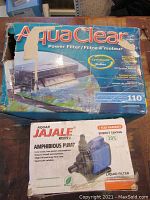Photo of AquaClear 110 Power Filter box with visible wear and inclusion of Aquajala Amphibious Pump box showing product info and warranty.