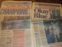 Two Sunday Star newspapers side by side with headlines about Blue Jays' World Series Championships in 1992 and 1993 on a wooden surface.