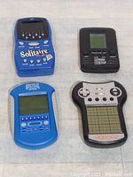 Photo showing 4 different vintage handheld electronic games arranged in a 2x2 layout on a white surface.