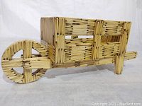 Front-left angle view of the wheelbarrow sculpture showing circular wheel, rectangular container body, and handles extended in front.