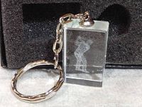 Crystal cube keychain showing 3D laser etched golfer inside with attached metal ring and chain, displayed in foam in original box.