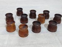 All 11 mini wooden containers arranged in rows on a light surface, displaying a variety of wood tones and smooth, rounded shapes.