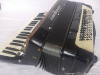 Full side view showing the piano keyboard, bellows, and part of button section on the left side of the accordion.