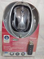 Front view of sealed Microsoft Wireless Notebook Presenter Mouse 8000 in packaging, showing mouse and USB receiver.