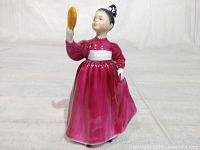 Front view of the figurine showing the pink dress and woman holding a mirror.