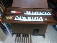 Full front view of the vintage Kimball Superstar III organ showing wooden cabinet, dual manuals, colored stops, foot pedals, and woven speaker grille.