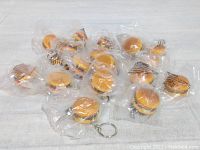 Lot of 19 individual new hamburger keychains, all wrapped in plastic, showing the full quantity and condition.