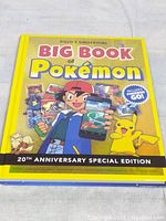 Front cover of the hardcover book with bright yellow background, Ash Ketchum and Pikachu, featuring title and promotional content for Pokémon Go.