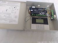 DSC PC2550 control panel inside beige metal enclosure, showing control board, wiring, and numeric keypad with LCD.