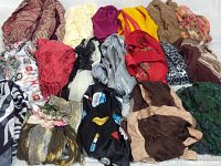 Seventeen scarves arranged on a surface showing various colors, patterns, and textures, including paisley, solid, and floral prints.