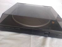 Front view of black Hitachi HT-MD30 turntable with dust cover closed, showing brand and model name.