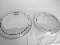 Two clear Remo drumheads, one 12-inch and one 10-inch, shown side by side on a white surface.
