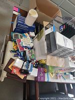 Overview of various office supplies displayed on a table including pens, calculators, notebooks, and desk organizers.
