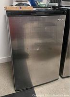 Full front view of compact refrigerator showing stainless door and black frame.