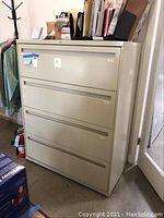 Full frontal view of a beige four-drawer lateral file cabinet by HON in an office setting.