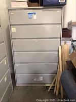 Front view of the grey metal six drawer lateral file cabinet, showing full height and six drawer fronts with small labels.
