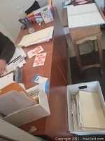 View of desk top with papers, files, desk calendar, and other office items on surface.