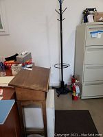Photo showing wooden dictionary stand next to office desk, with coat rack partially visible on right