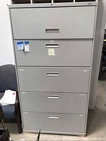 Front view of the tall metal vertical filing cabinet with five drawers and recessed handles.