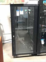 Front view of the server storage cabinet with glass door showing lock, keys, and interior shelf with cables.