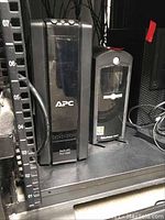 Front view of APC Back-UPS Pro 1500 unit on a shelf, showing front panel and some control buttons.