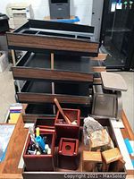 Photo showing wooden desk organizers with compartments, manual scale, and two rough mineral stones on a table.
