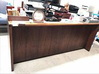 Side angle of the wooden credenza showing smooth wood veneer and top surface with office items