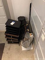 Stacking trays, stools, circular metal fan, briefcases and boxes near filing cabinets