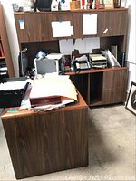 Front angle photo showing wood grain desk and detachable hutch with paperwork on desk surface.