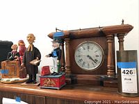 Showing the wood carved legal figurines, wooden clock, and metal mechanical bank on top of furniture