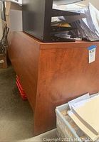 Side view of wooden desk with medium brown finish, showing sturdy construction and side panel with visible wood grain