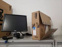 Dell 17-inch monitor with power and video cables beside Dell E1910H packaging box.