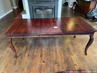 Rectangular wood dining table with leaf inserted viewed from front