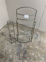 Full view of both metal bathroom racks; a towel rack with bottom shelf and a toilet paper holder stand