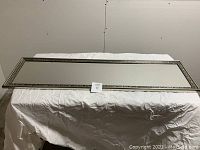 Full view of the rectangular mirror from the front laid on a white cloth.