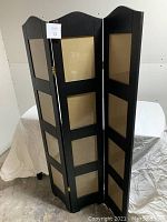 Front angled view of accordion style photo stand showing black wood frame with glass fronts and hinges