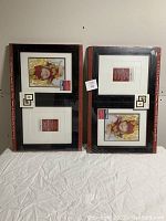 Two sets of two black and brown picture frames, shrink-wrapped in plastic, showing the front with sample art and mat openings.