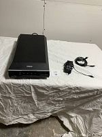 Full view of Epson flatbed scanner, power adaptor and USB cable laid out on white surface