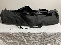 Black nylon carrying bag with shoulder strap containing tripods