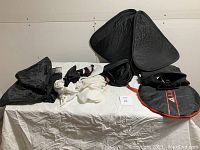 Full lot of camera lighting equipment including reflectors and diffusers laid out on a white cloth.