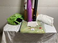 Overall lot on table showing green bag, fabric, backdrops, and large unopened package