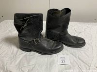 Side view of the pair of black leather Frye boots showing buckle details and fold-over tops.