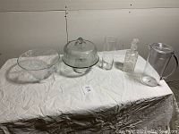 Full set of glassware and plastic juice jug displayed on table with white cloth